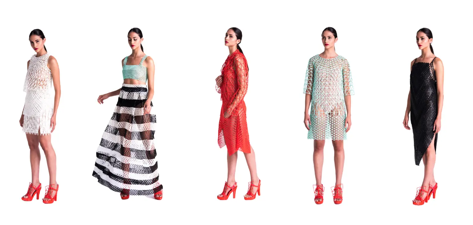 A lineup of five female models standing against a white background, each wearing a different 3D-printed, open-weave mesh garment in various colors including white, mint green, red, and black. All models are wearing bright red high-heeled shoes.