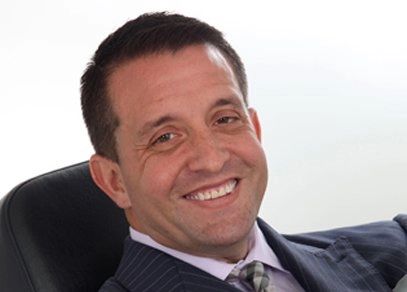 A man in a business suit leans back in his office chair with a smile. Alan T. Brown: A vacation changed his life.