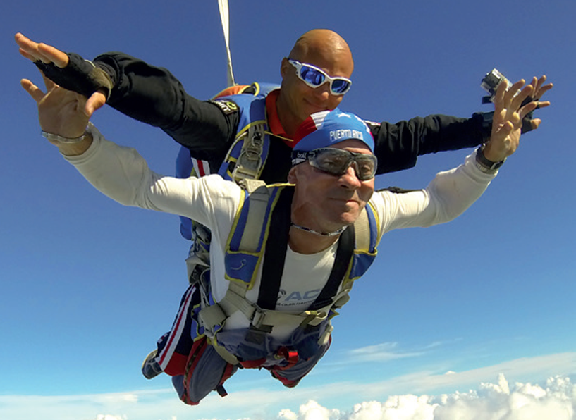Accessible Martinique is accompanied by a photo of two men tandem-skydiving under a vibrant blue sky.