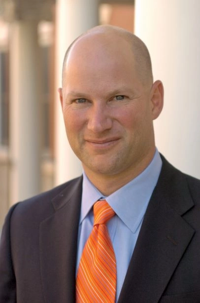 Photo is a headshot of a man in a blue suit with an orange tie. Headline states, Interview with Charlie Hammerman.