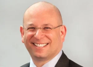 Headshot of a smiling man in a suit. Text reads, Howard Rosenblum: A life of advocacy.
