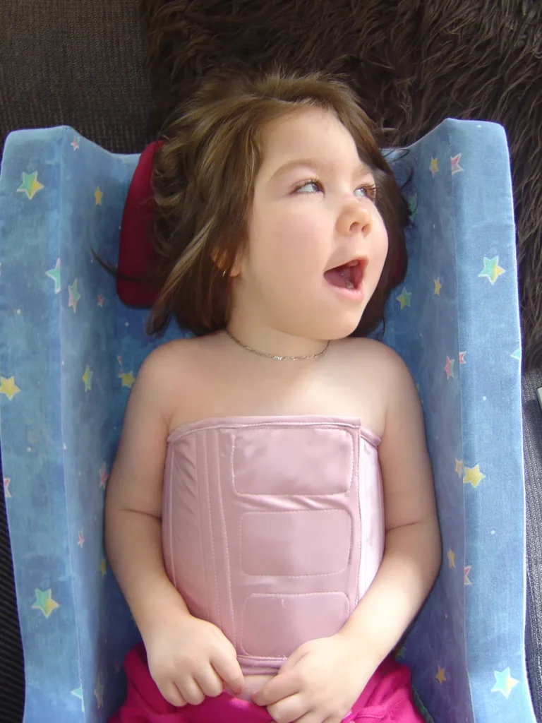 A smiling toddler is nestled in a curved device which is blue and patterned with stars.