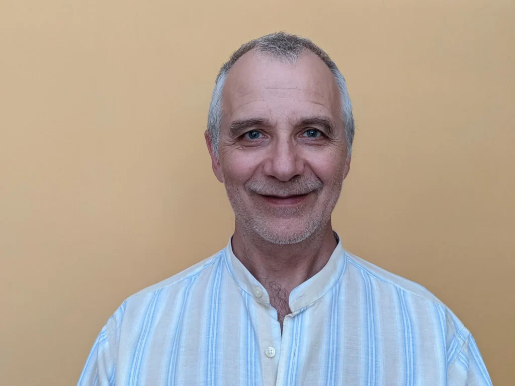 A man in a blue and white striped shirt smiles for the camera.