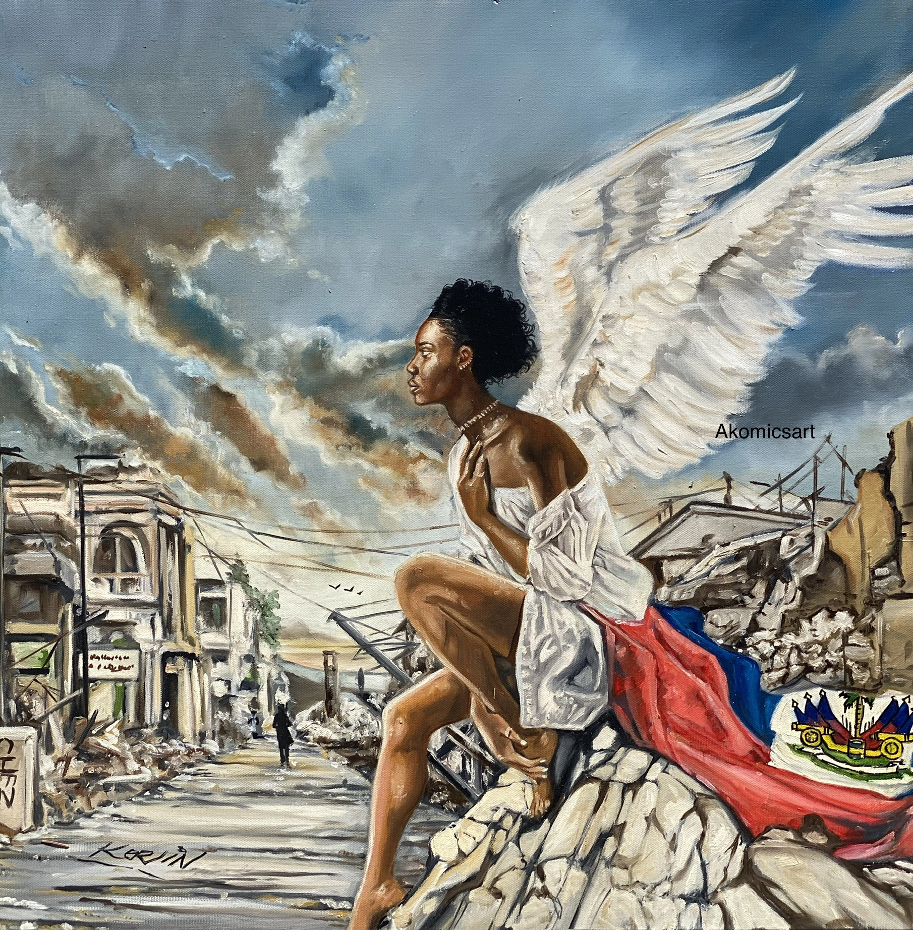 A powerful oil painting, potentially depicting the aftermath of a natural disaster or conflict in Haiti. A Black woman with large white angel wings sits barefoot on a pile of rubble. She is draped in a white garment and wrapped in the red and blue Haitian flag. She gazes contemplatively over a street lined with partially collapsed buildings under a stormy, cloud-filled sky. The Haitian coat of arms is visible on the flag. Signatures "Akomicsart" and "Kerlin" are present.