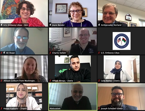 A screenshot of a 12-person video conference call (Zoom meeting style) showing various individuals in separate video boxes, many labeled with names and affiliations such as "U.S. Embassy Libya," "Ambassador Norland," "Joyce Bender," and "USAID." The participants are smiling and engaged in the call.