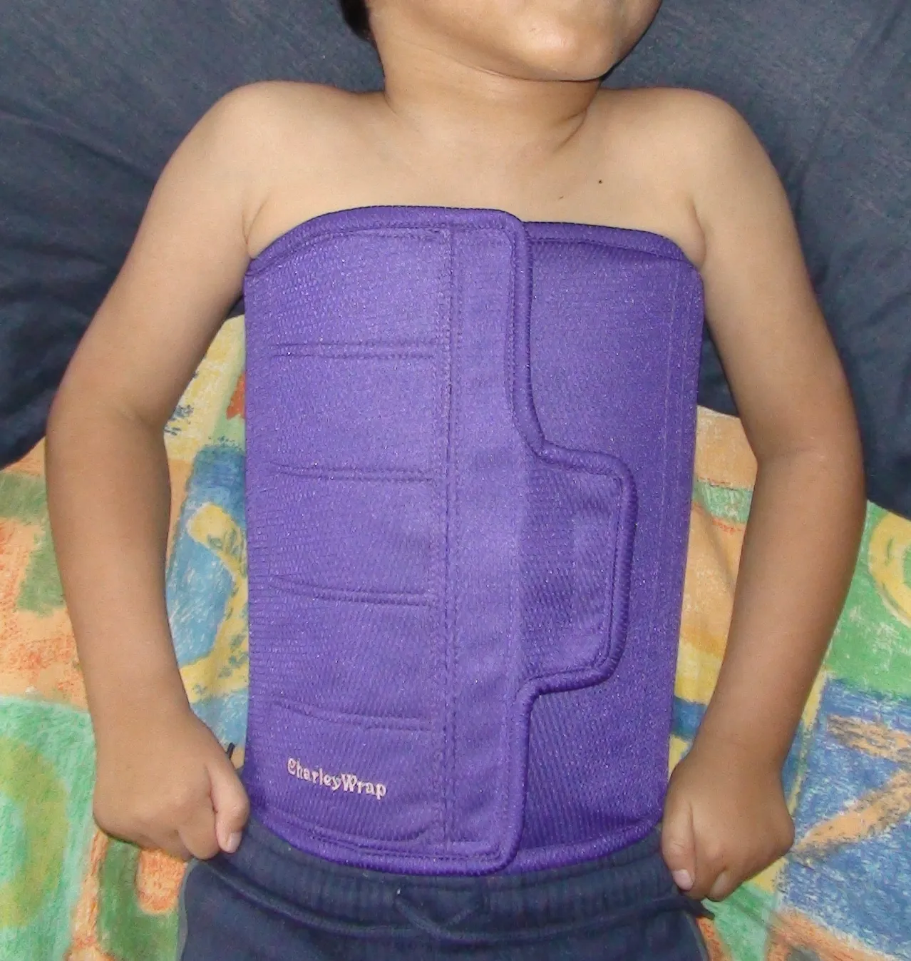 oung child wearing a purple CharleyWrap compression or therapy band around their abdomen, used for core support or sensory input.