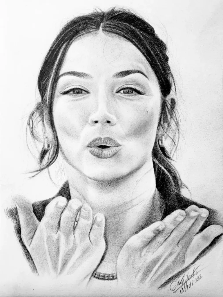 A realistic black and white pencil drawing of a woman, possibly Ana de Armas, blowing a kiss, with her hands cupped outward toward the viewer.