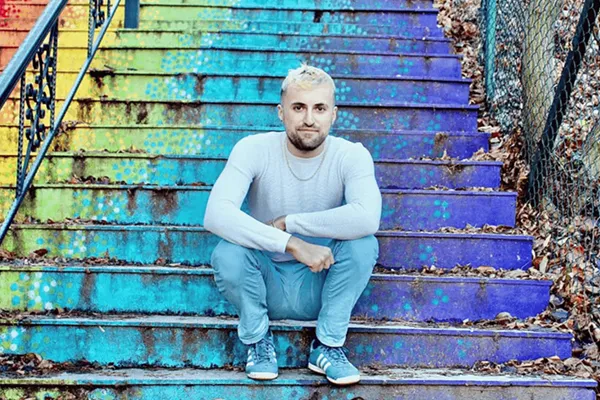 A man with spiky blonde hair and casual clothes sits on a set of steps that are painted in green, blue and purple. The headline is California has got me dreaming. As an autic solo traveler, I have been to many of our earth's most breathtaking sites. However. . . Orange text invites us to Read More.