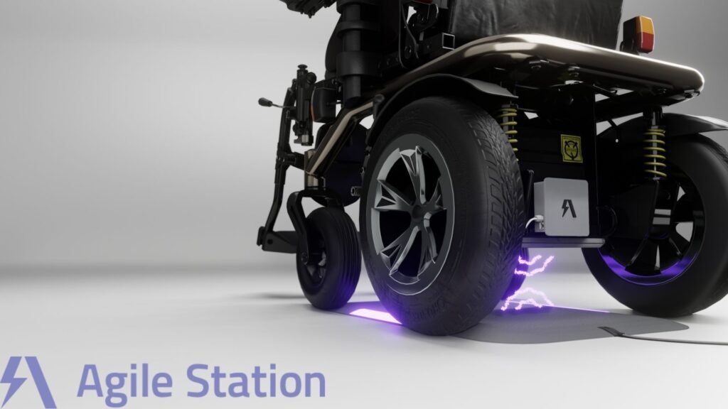 A close-up of a sleek, modern electric wheelchair featuring large, sturdy tires and shock absorbers. The image highlights a charging pad on the ground beneath the wheelchair, emitting a faint purple glow and lightning-like effect, indicating wireless charging in progress. The wheelchair is branded with the logo "Agile Station" in the bottom left corner, with a stylized "A" icon. The design suggests a focus on innovation, mobility, and advanced technology.