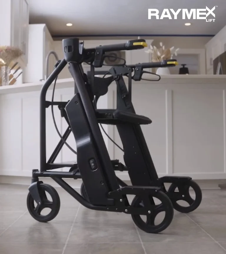 The image shows a sleek, black mobility aid, possibly a rollator or walker, with a modern and ergonomic design. It features four wheels, a seat, and handles equipped with controls, suggesting some advanced functionality. The design looks sturdy and practical, with a focus on both mobility and support for users. The logo "RAYMEX Lift" is displayed in the upper right corner, indicating the brand of the product. The background appears to be a clean, modern kitchen setting with neutral tones, emphasizing a lifestyle context for the product.