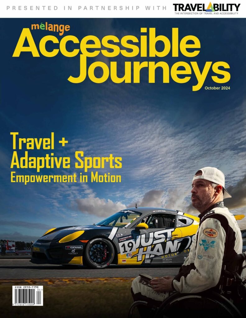 The cover of the magazine "mélange Accessible Journeys" (October 2024 edition) features a powerful image that promotes "Travel + Adaptive Sports" under the tagline "Empowerment in Motion." The cover showcases a sleek race car with the logo "Just Hands" prominently displayed on the side, and a man in a racing suit, sitting in a wheelchair, looking determinedly at the viewer. The cover is presented in partnership with TravelAbility, highlighting the intersection of travel and accessibility. The background shows a clear sky, adding to the empowering and inspirational theme of the cover.