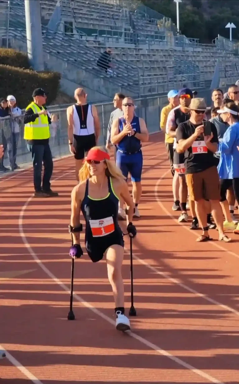 An athlete on a running track, confidently competing with the aid of crutches, with spectators in the background.