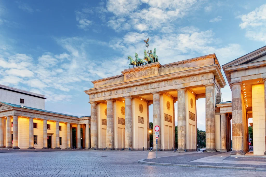 The iconic Brandenburg Gate in Berlin, featuring classical columns and a chariot sculpture against a beautiful sky.