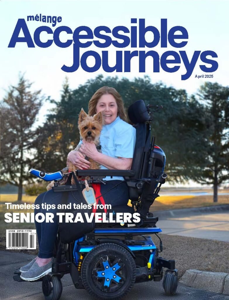 Cover of the April 2025 issue of mélange Accessible Journeys magazine. A smiling woman sits in a motorized wheelchair outdoors, holding a small dog in her arms. She has shoulder-length light brown hair and is wearing a light blue shirt and dark pants. The dog is a Yorkshire Terrier. Behind them are trees and a sidewalk. The headline reads, "Timeless tips and tales from SENIOR TRAVELLERS." The magazine's title is displayed prominently at the top in bold blue text.