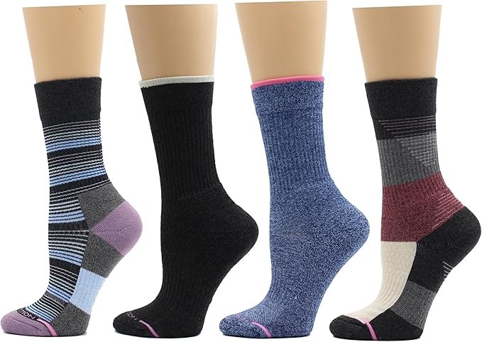 "Four pairs of women's crew socks displayed on mannequin legs, each featuring a different design and color pattern including stripes, solid black, heathered blue, and geometric blocks in shades of purple, blue, gray, black, and cream."
