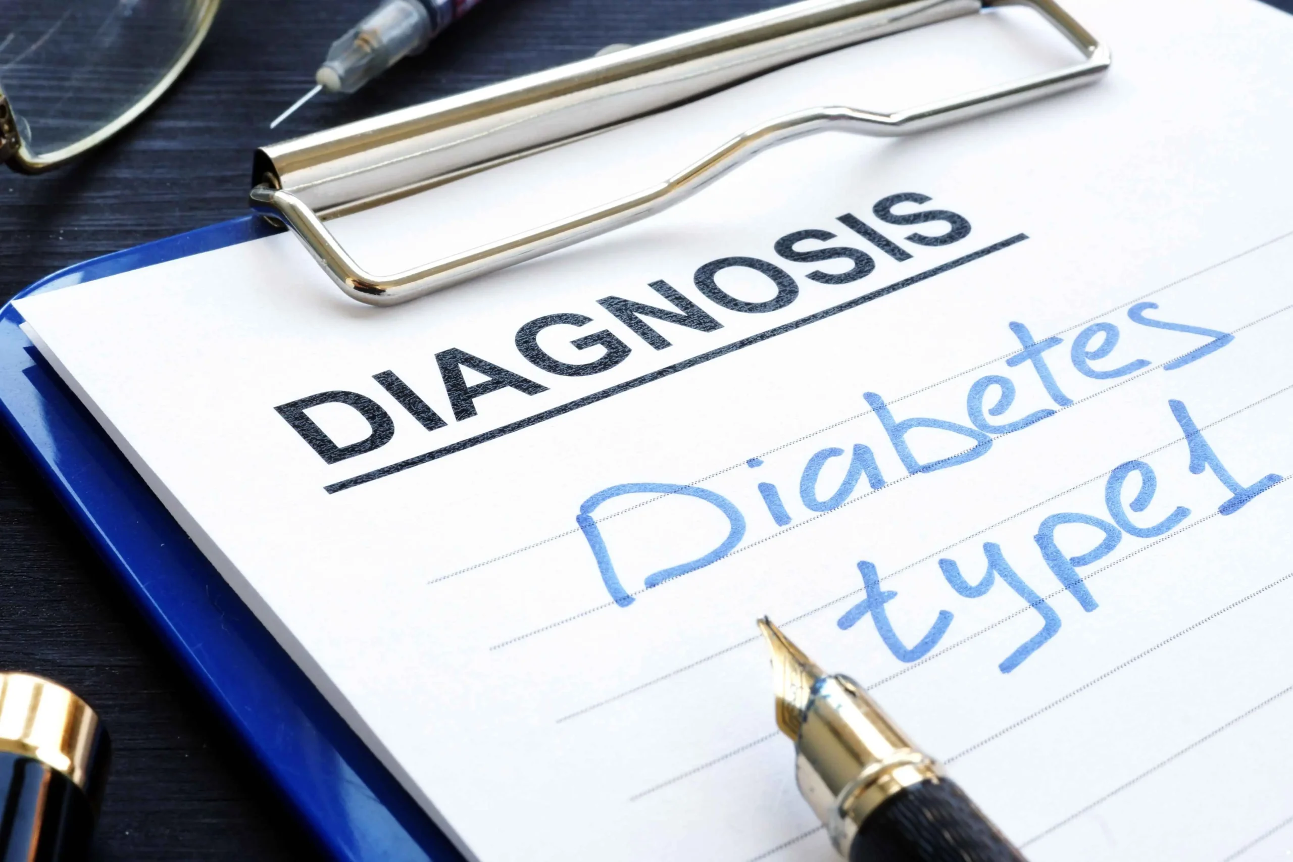 A clipboard with a diagnosis note reading "Diabetes type 1," accompanied by a pen and syringe on a dark background.