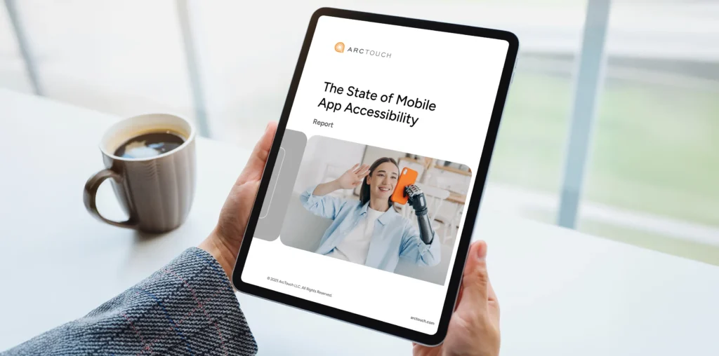 A person holding a tablet displaying a report titled "The State of Mobile App Accessibility," with a coffee mug nearby.