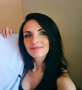 A person with long, dark hair is holding a piece of fabric against their body, set against a neutral-toned background.