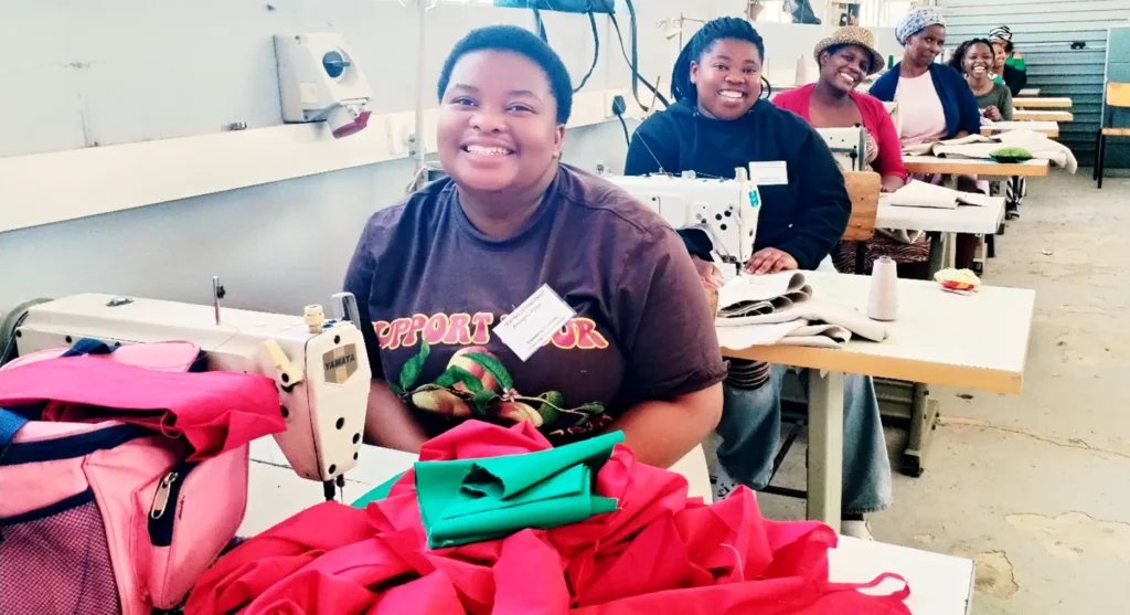A classroom filled with sewing machines where individuals work on colorful fabric and projects, enhancing their sewing skills.