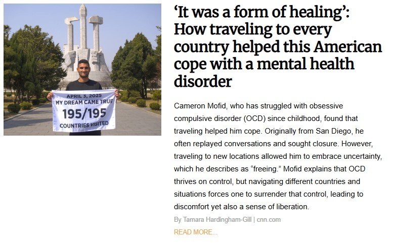 Cameron Mofid stands in front of a monument holding a banner reading “195/195 Countries Visited,” celebrating his journey of traveling to every country in the world as a way to cope with OCD and promote mental health healing through global exploration.