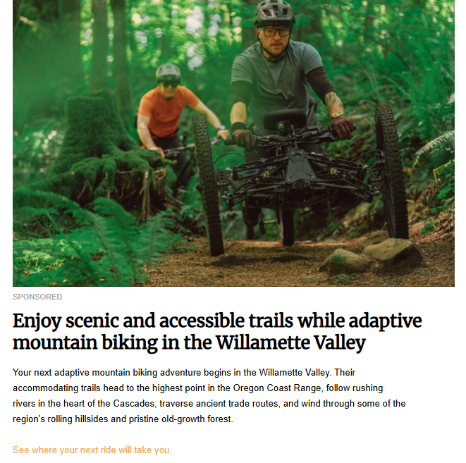 Two people on four-wheeled adaptive mountain bikes ride on a dirt path through a lush forest. The image is for a sponsored post about accessible mountain biking trails.