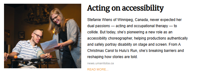 A woman with glasses stands next to a man in a wheelchair, both looking down at some papers she is holding. The woman is smiling at the man, who is also smiling. They are indoors, with a warm, dim light.