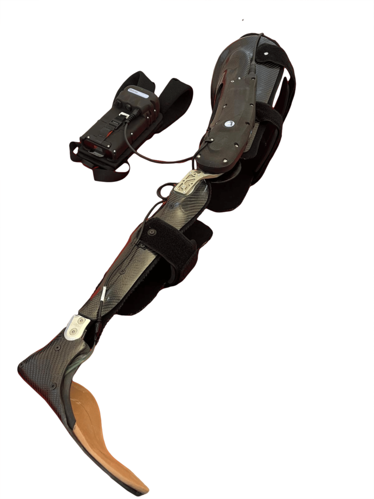 A close-up shot of a sleek, black Knee Ankle Foot Orthosis (KAFO), which appears to be a powered or bionic brace. The device is constructed primarily from carbon fiber, featuring knee and ankle joints, and straps for attachment to the leg. A separate electronic control unit, connected by a wire, is visible near the top left. The entire assembly is set against a solid black background, highlighting the device's technical and angular design.
