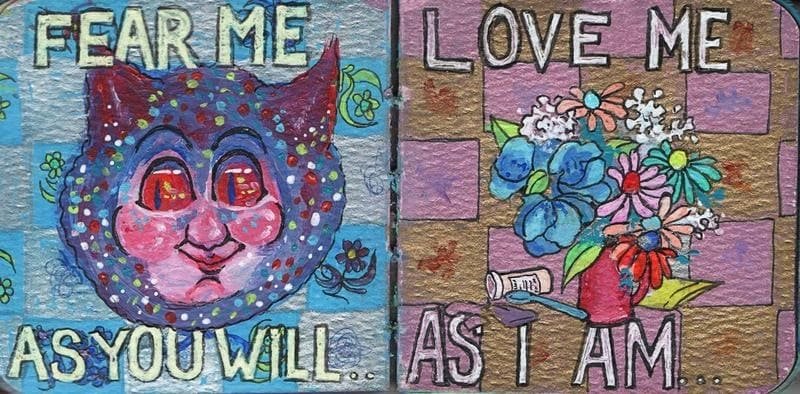 A diptych (two-panel painting) featuring colorful, expressive folk art style. The left panel, against a blue checkered background, features a whimsical, colorful cat face with large eyes and a mischievous expression, with the white block text "FEAR ME AS YOU WILL." The right panel, against a pink and brown checkered background, shows a bouquet of blue, pink, and white flowers in a red vase, along with the white block text "LOVE ME AS I AM."