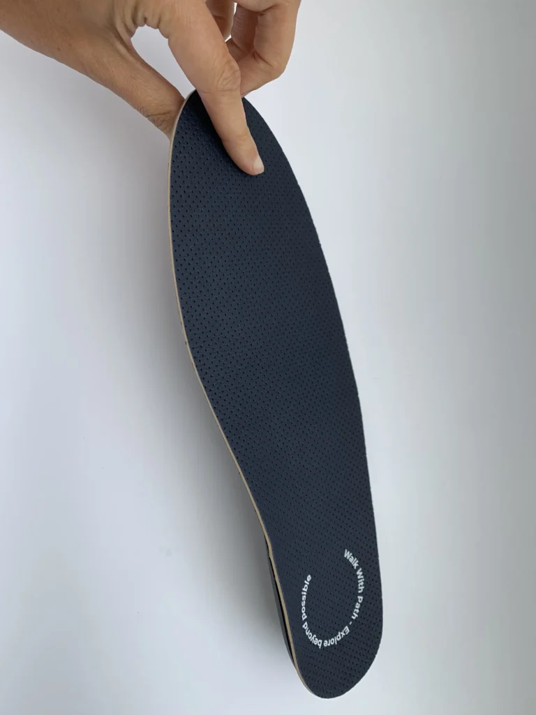 Close-up view of a high-tech smart shoe insole for diabetes foot health, showing a textured black surface and ergonomic design.