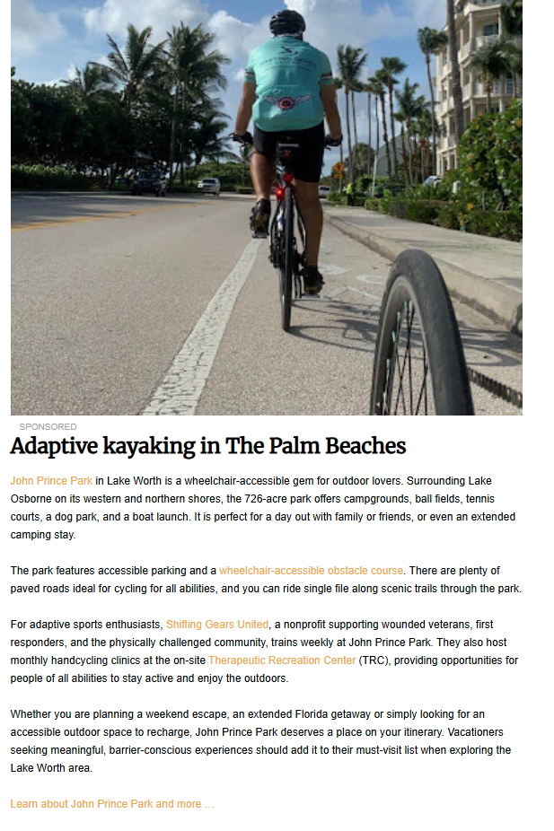 A low-angle, point-of-view photograph from behind a cyclist on a paved path, with a partial view of a bicycle wheel in the foreground and palm trees lining the road under a bright sky. Below the image, a sponsored article titled "Adaptive kayaking in The Palm Beaches" describes the accessible amenities of John Prince Park in Lake Worth and the work of the nonprofit Shifting Gears United.